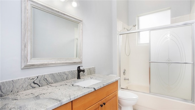 full bathroom featuring vanity, bath / shower combo with glass door, and toilet