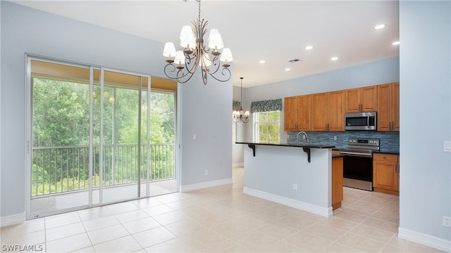 kitchen featuring appliances with stainless steel finishes, backsplash, decorative light fixtures, an inviting chandelier, and a breakfast bar area