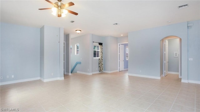 empty room with visible vents, arched walkways, and baseboards