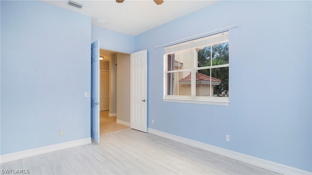 empty room featuring ceiling fan, wood finished floors, visible vents, and baseboards