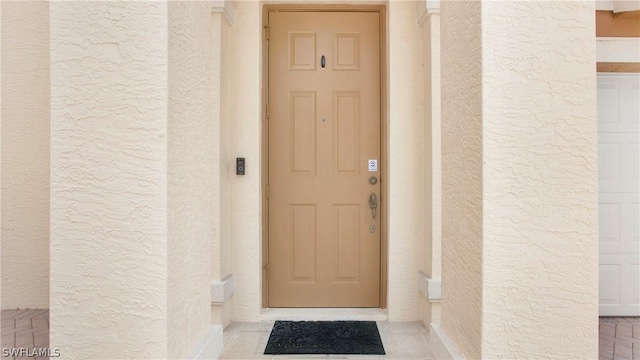 property entrance featuring a garage and stucco siding