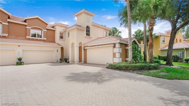 mediterranean / spanish home with decorative driveway, a tile roof, and stucco siding