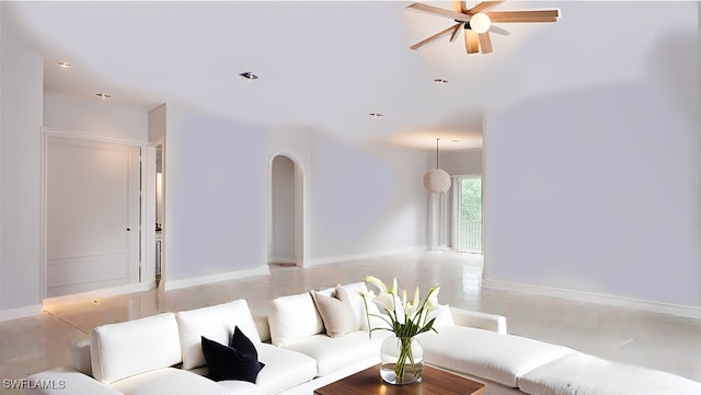 living area with arched walkways, ceiling fan, and baseboards