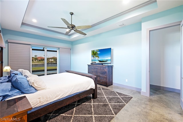 bedroom featuring ceiling fan, a tray ceiling, and concrete floors