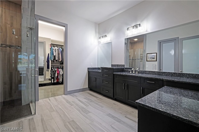 bathroom featuring wood-type flooring, double vanity, and walk in shower