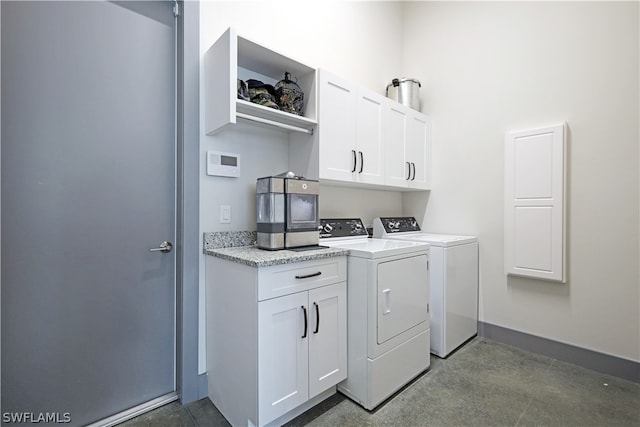 clothes washing area with separate washer and dryer and cabinets