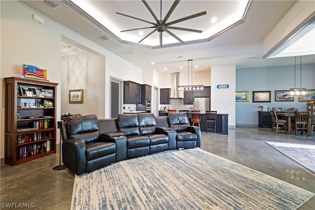 living room featuring a tray ceiling and ceiling fan with notable chandelier