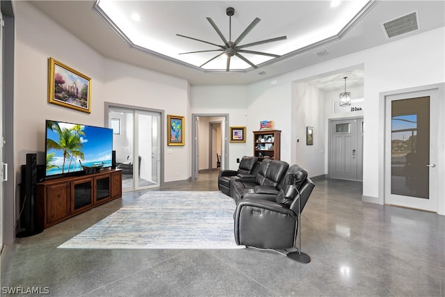 living room featuring concrete flooring, a tray ceiling, french doors, and ceiling fan with notable chandelier