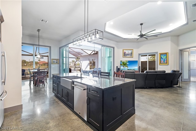 kitchen with an island with sink, a tray ceiling, sink, and appliances with stainless steel finishes