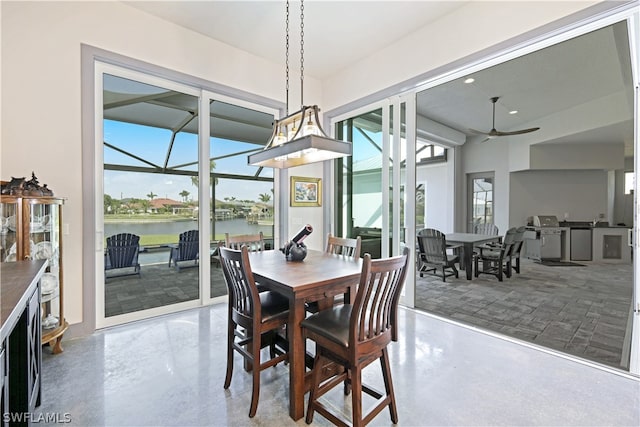 dining room featuring ceiling fan, concrete flooring, and a water view