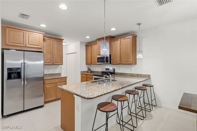 kitchen with kitchen peninsula, a breakfast bar area, light stone countertops, pendant lighting, and appliances with stainless steel finishes