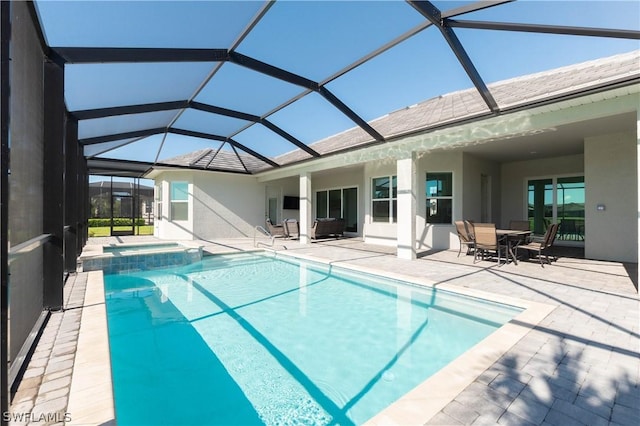 view of swimming pool featuring a patio area, glass enclosure, and an in ground hot tub