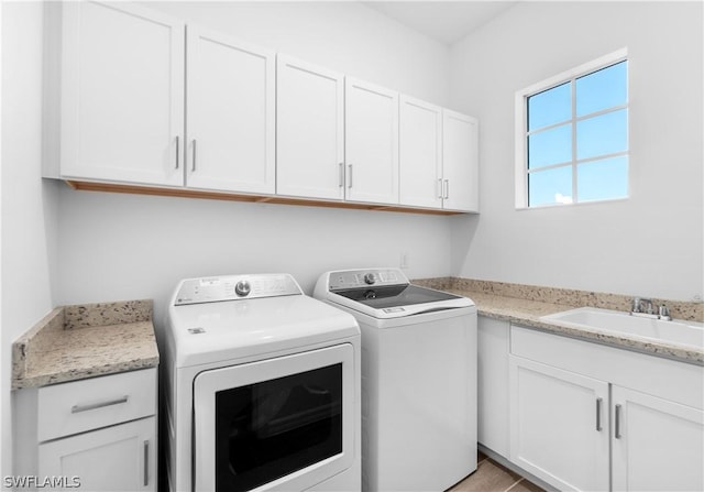 laundry room with cabinets, light tile patterned floors, washing machine and clothes dryer, and sink