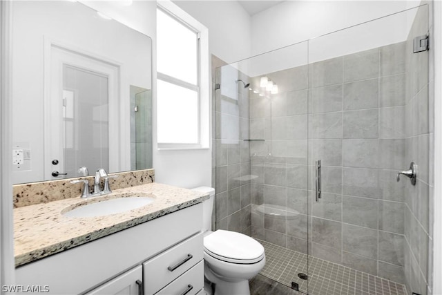 bathroom featuring toilet, a shower with shower door, and vanity