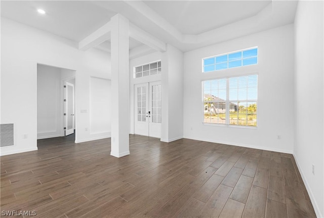 unfurnished living room with a high ceiling, dark wood-type flooring, and french doors