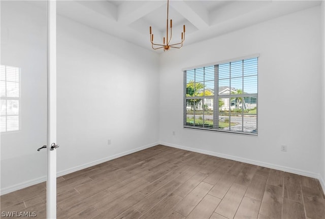 unfurnished room featuring hardwood / wood-style flooring, a chandelier, beam ceiling, and coffered ceiling