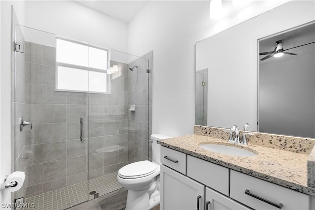 bathroom featuring ceiling fan, walk in shower, vanity, and toilet