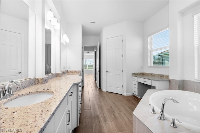 bathroom with hardwood / wood-style flooring, a relaxing tiled tub, plenty of natural light, and vanity