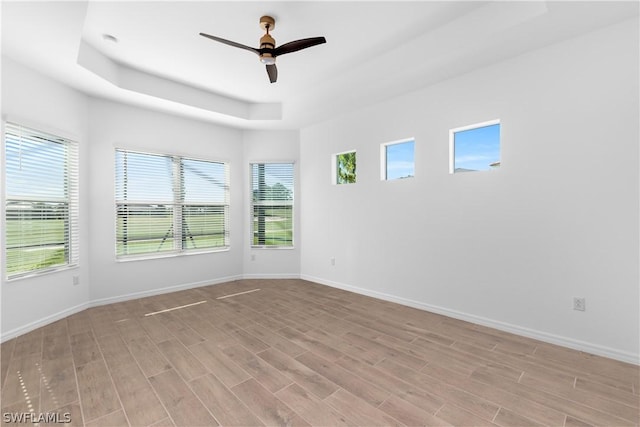 spare room with ceiling fan, light hardwood / wood-style floors, and a tray ceiling