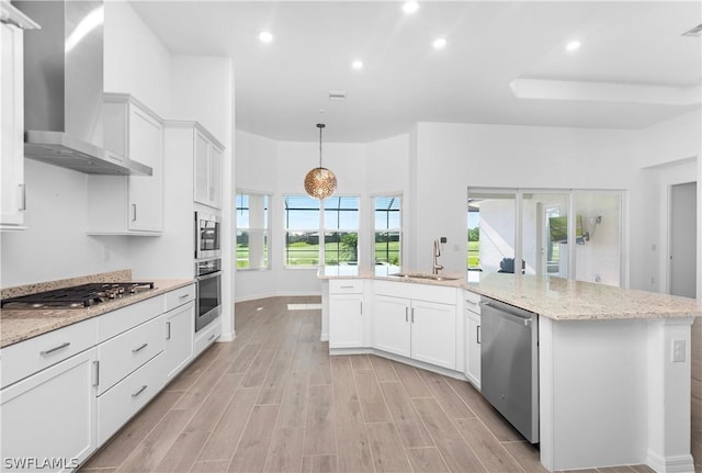 kitchen featuring sink, white cabinetry, appliances with stainless steel finishes, and wall chimney exhaust hood