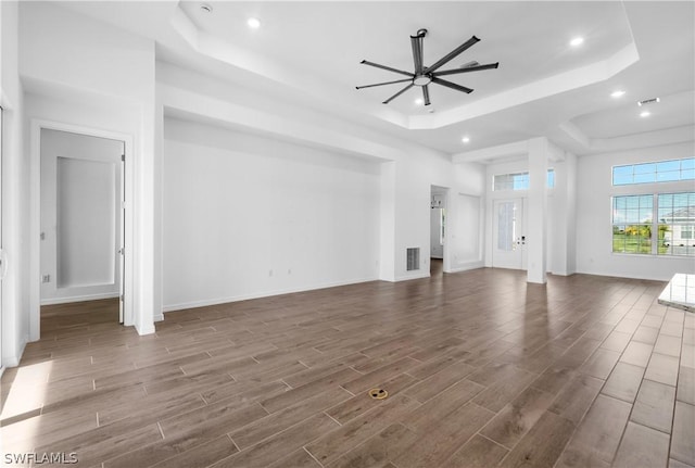 unfurnished living room with ceiling fan and a raised ceiling