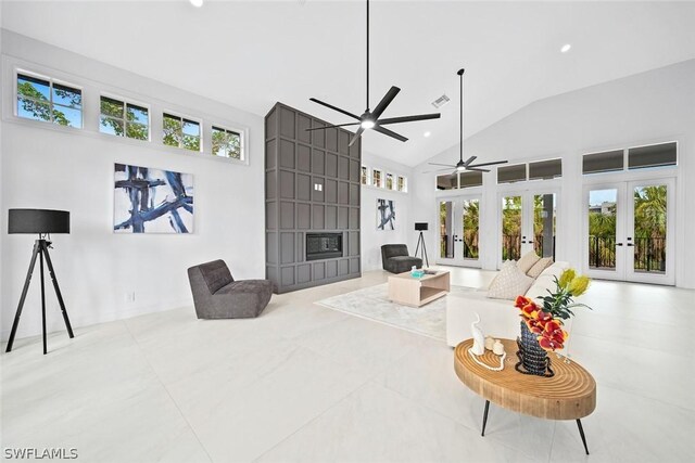 living room with high vaulted ceiling, a large fireplace, a wealth of natural light, and french doors