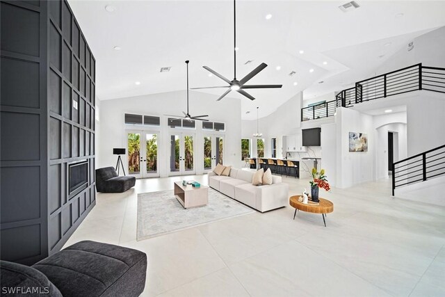 tiled living room with ceiling fan, french doors, and a high ceiling