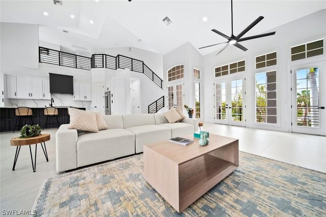 living room with ceiling fan, french doors, a high ceiling, and plenty of natural light