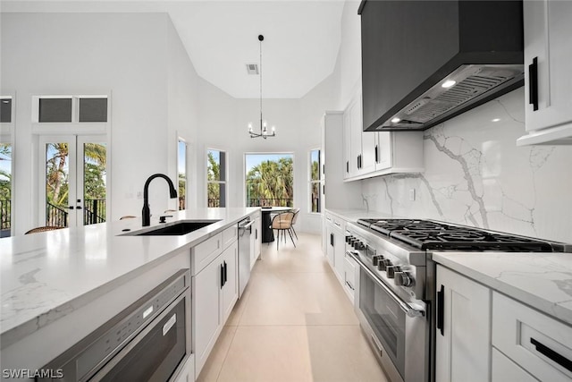 kitchen featuring white cabinets, appliances with stainless steel finishes, custom exhaust hood, decorative light fixtures, and sink