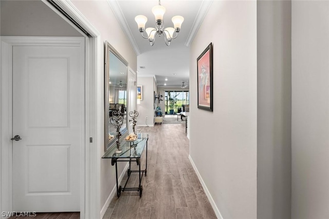 hallway with hardwood / wood-style floors, crown molding, and an inviting chandelier