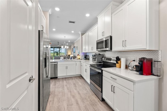 kitchen featuring backsplash, kitchen peninsula, white cabinetry, and stainless steel appliances