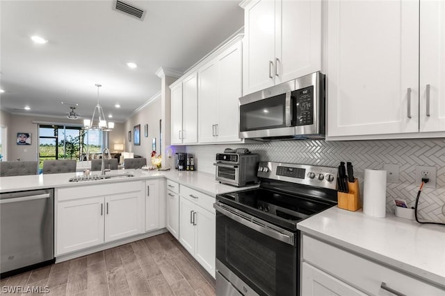 kitchen with white cabinets, crown molding, sink, decorative backsplash, and appliances with stainless steel finishes