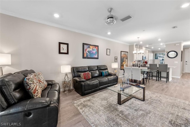 living room with ceiling fan with notable chandelier, light wood-type flooring, and ornamental molding