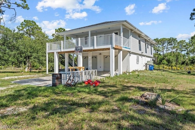 rear view of property featuring a wooden deck, a yard, and a patio