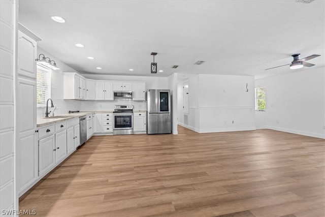 kitchen with decorative light fixtures, light hardwood / wood-style flooring, ceiling fan, appliances with stainless steel finishes, and sink