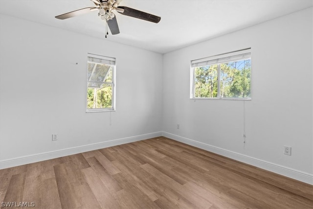 spare room with ceiling fan, a wealth of natural light, and wood-type flooring