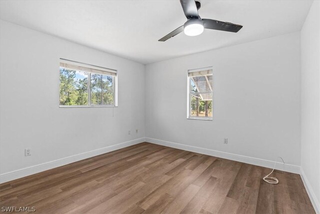 empty room featuring a healthy amount of sunlight, ceiling fan, and hardwood / wood-style floors