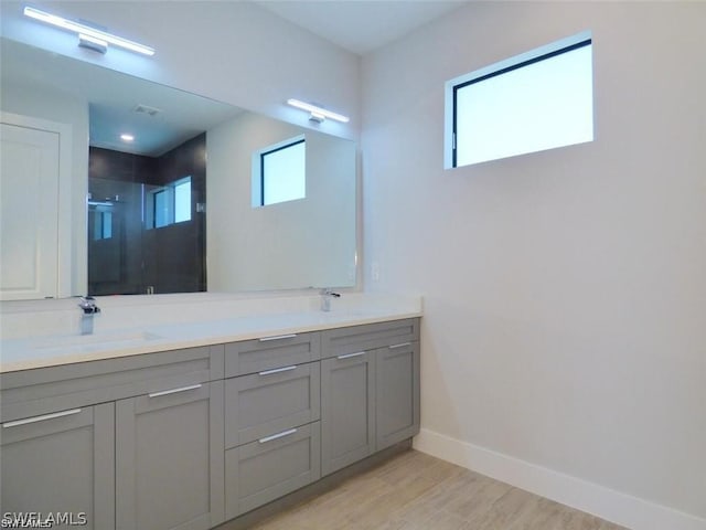 bathroom with hardwood / wood-style flooring, walk in shower, and vanity