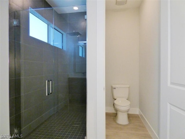 bathroom featuring toilet and a shower with door