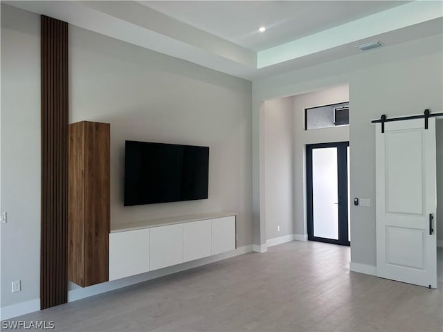 unfurnished living room featuring light hardwood / wood-style flooring and a barn door