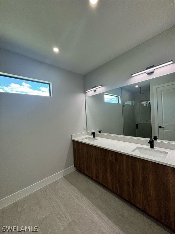 bathroom with a shower with shower door, hardwood / wood-style floors, and vanity