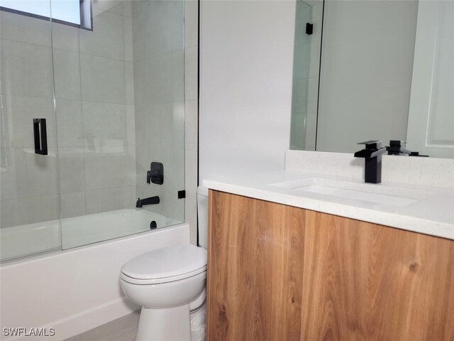 bathroom featuring toilet, shower / bath combination with glass door, and vanity