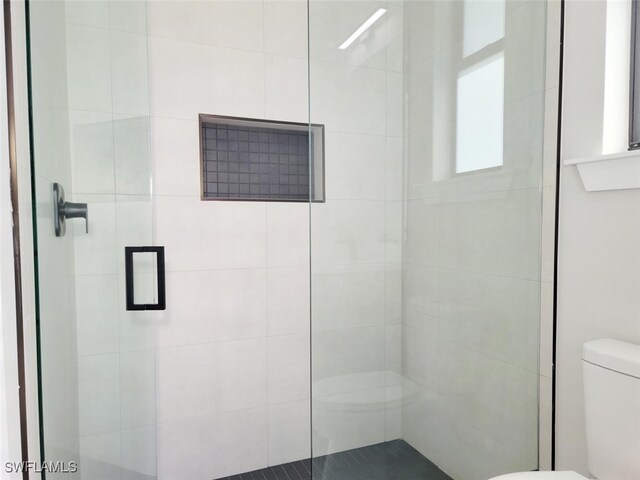 bathroom featuring toilet and a shower stall