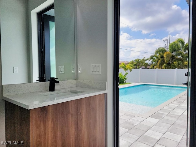 view of swimming pool featuring a fenced in pool, a patio area, a sink, and fence