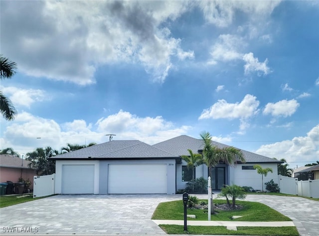 ranch-style house with a garage, a gate, fence, decorative driveway, and stucco siding