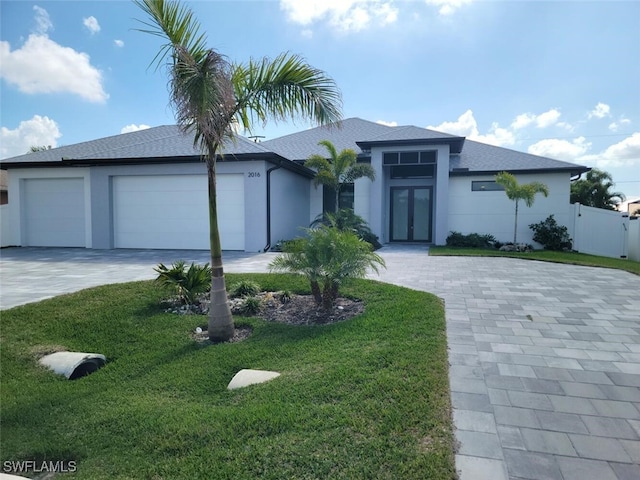 prairie-style house with a garage, stucco siding, decorative driveway, and a front yard