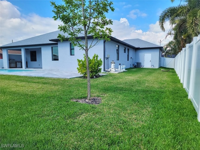 back of house featuring central AC, a lawn, a patio area, and a fenced backyard