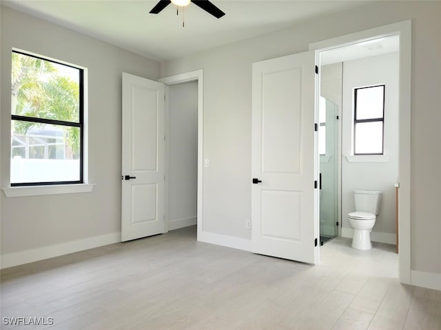 unfurnished bedroom featuring light wood-style flooring, baseboards, and connected bathroom