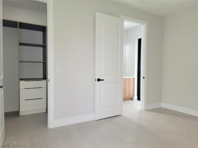 unfurnished bedroom featuring light wood-style floors, a closet, and baseboards