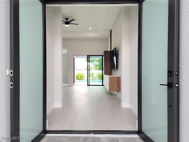 hall featuring a raised ceiling and baseboards